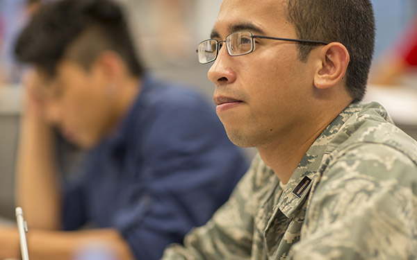 A UWF student in military uniform listens in class.