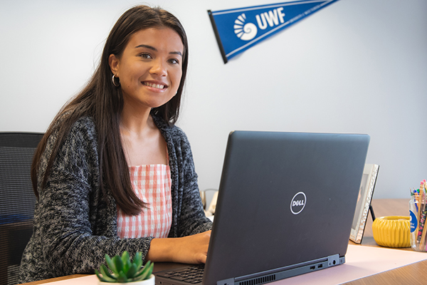 uwf student at a desk working on a laptop