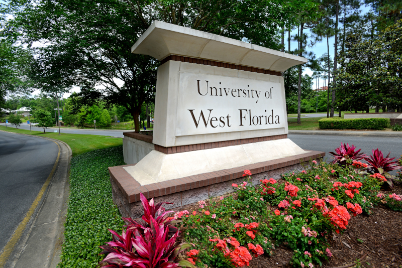 The University of West Florida main entrance has a concrete sign and pink flowers.