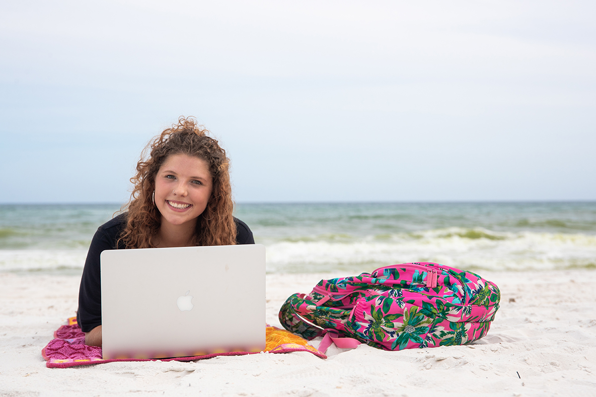Student with laptop on the beach
