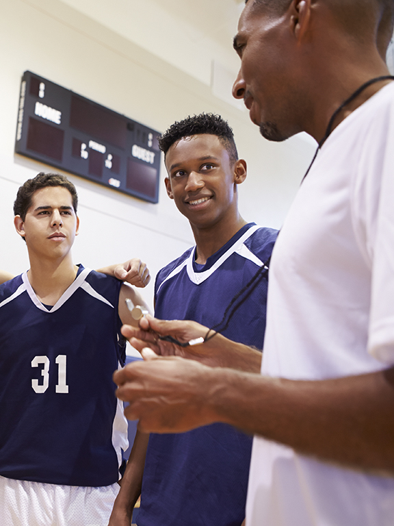High School Basketball Team Having Team Talk With Coach