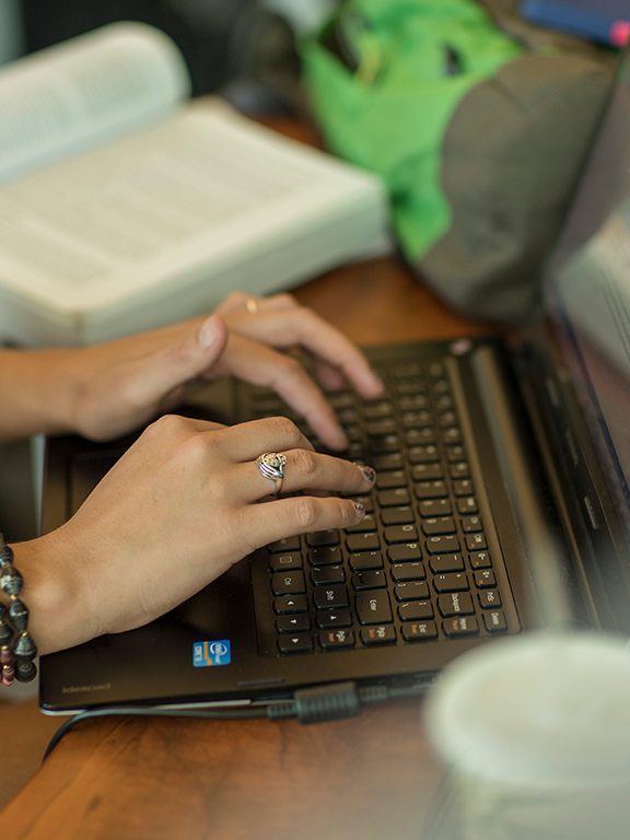 Online student hands on laptop keyboard