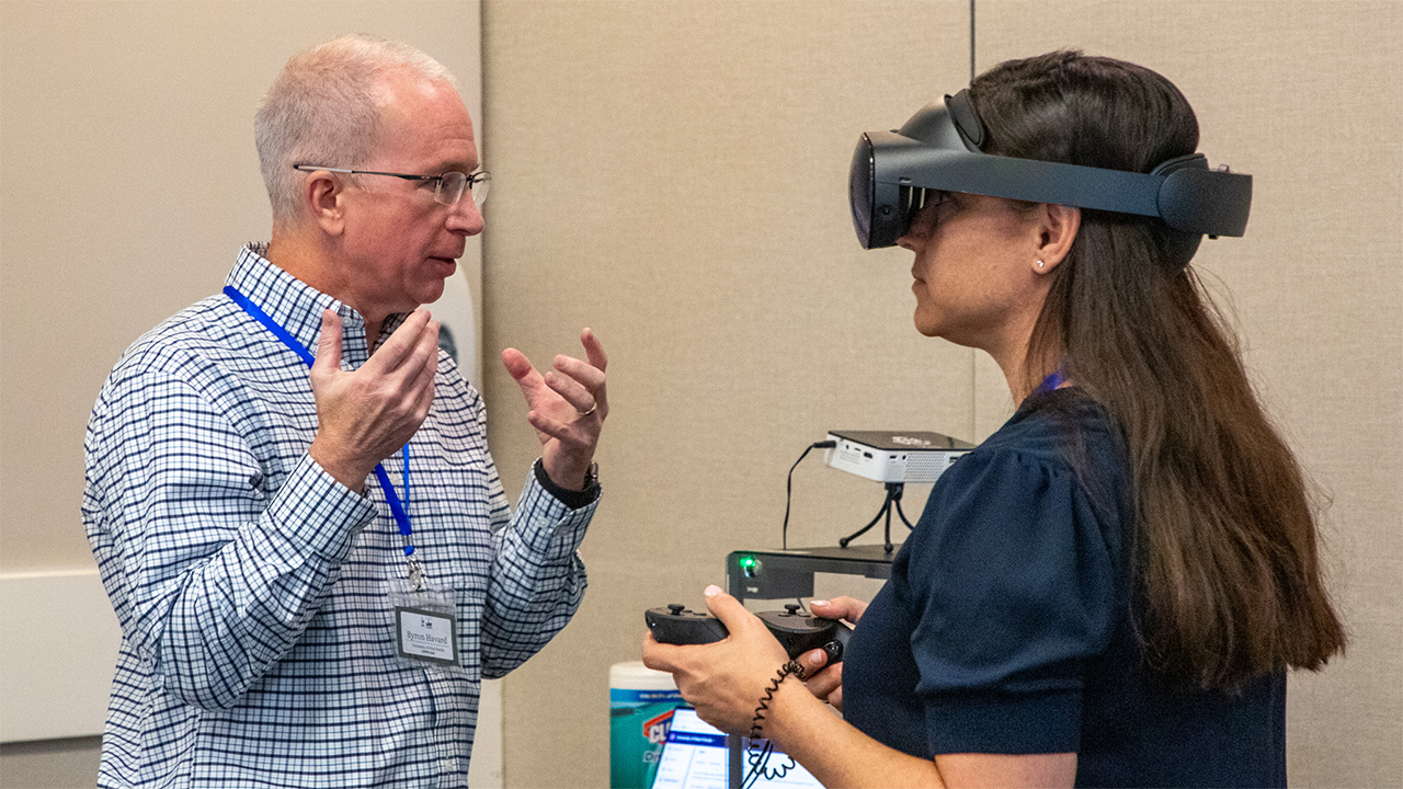 Dr. Havard demonstrates VR goggles to a faculty member.