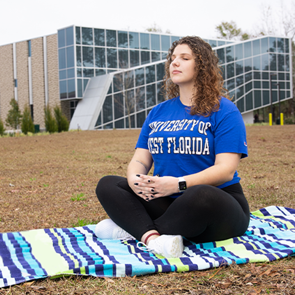 student meditating outside on-campus