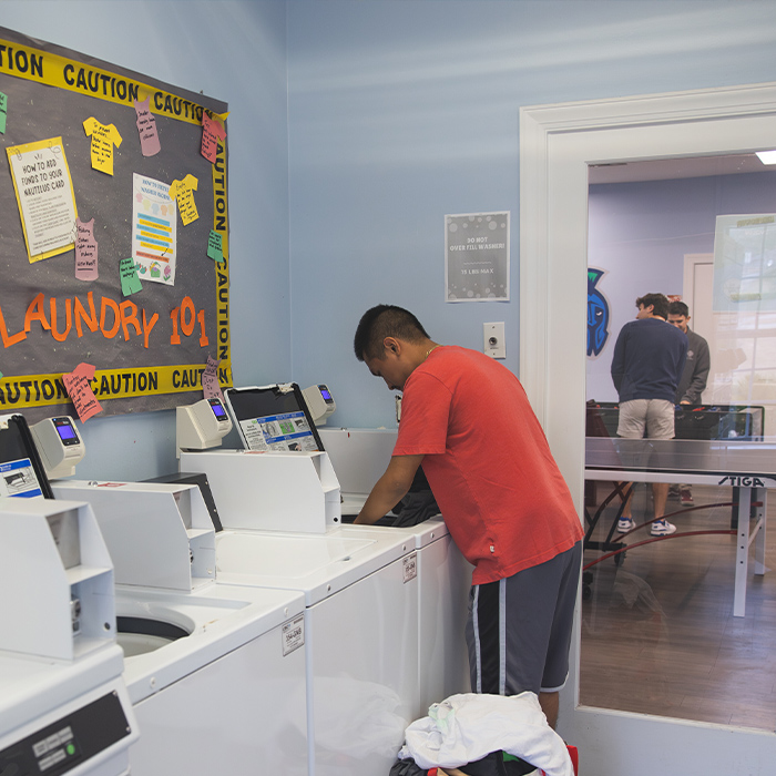student using laundry facility in the Village East Clubhouse