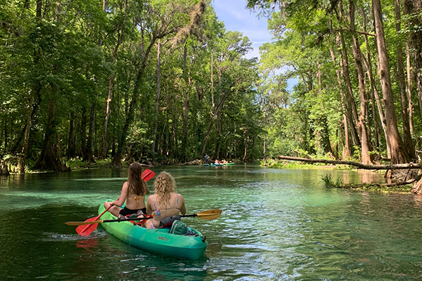 UWF Students kayaking in a river.