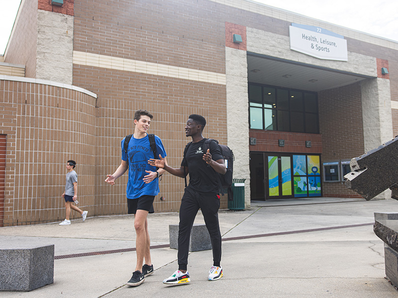 UWF Students walking in front of the Health, Leisure and Sports Facility