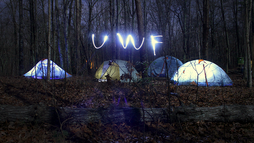 At night tents are set up with lights inside of them. Students are spelling out UWF OA using lights outside of the tents.