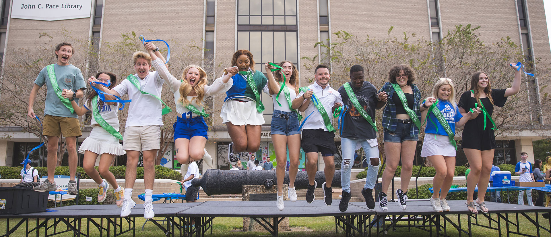 Students with Homecoming Court sashes jump in unison on Cannon Green
