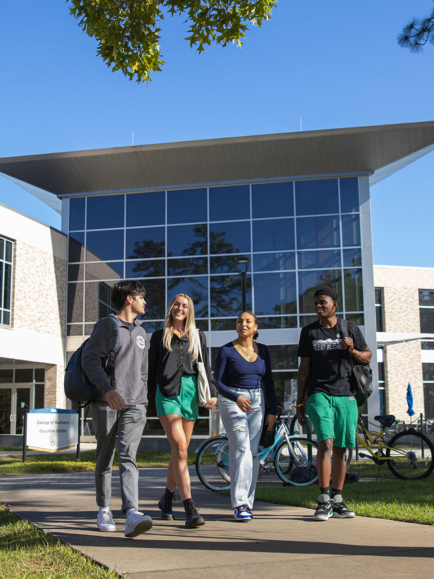 Students walk as a group in front of the College of Business.