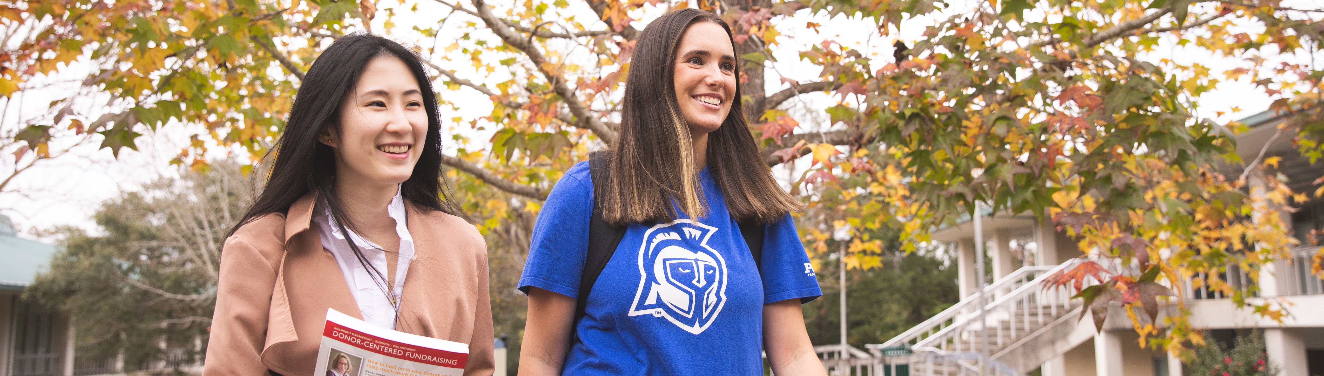 Two UWF students walk through campus during fall.