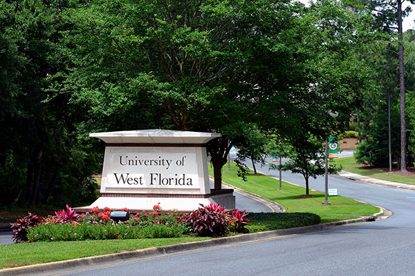 The main campus entrance features a University of West Florida sign surrounded by flowers in the median of University Parkway. 