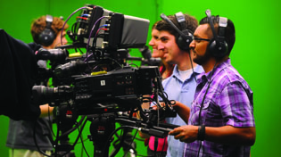 Students work behind the camera in a media lab.