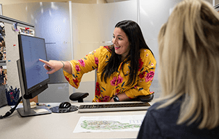 A staff member points out information on a computer to a student in Argo Central.