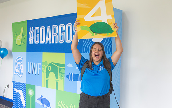 Orientation leader holding group sign and smiling