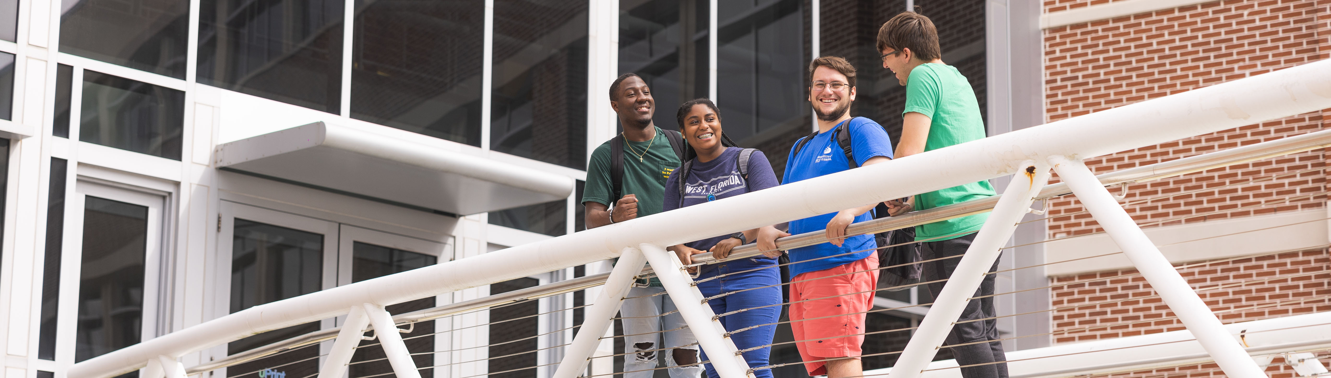 Students smile from bridge outside the Hal Marcus College of Science and Engineering.