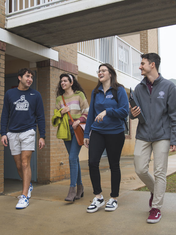 Four students walking and talking outside a dorm