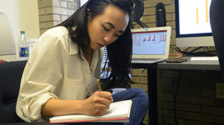 A student sits and writes in a notebook.