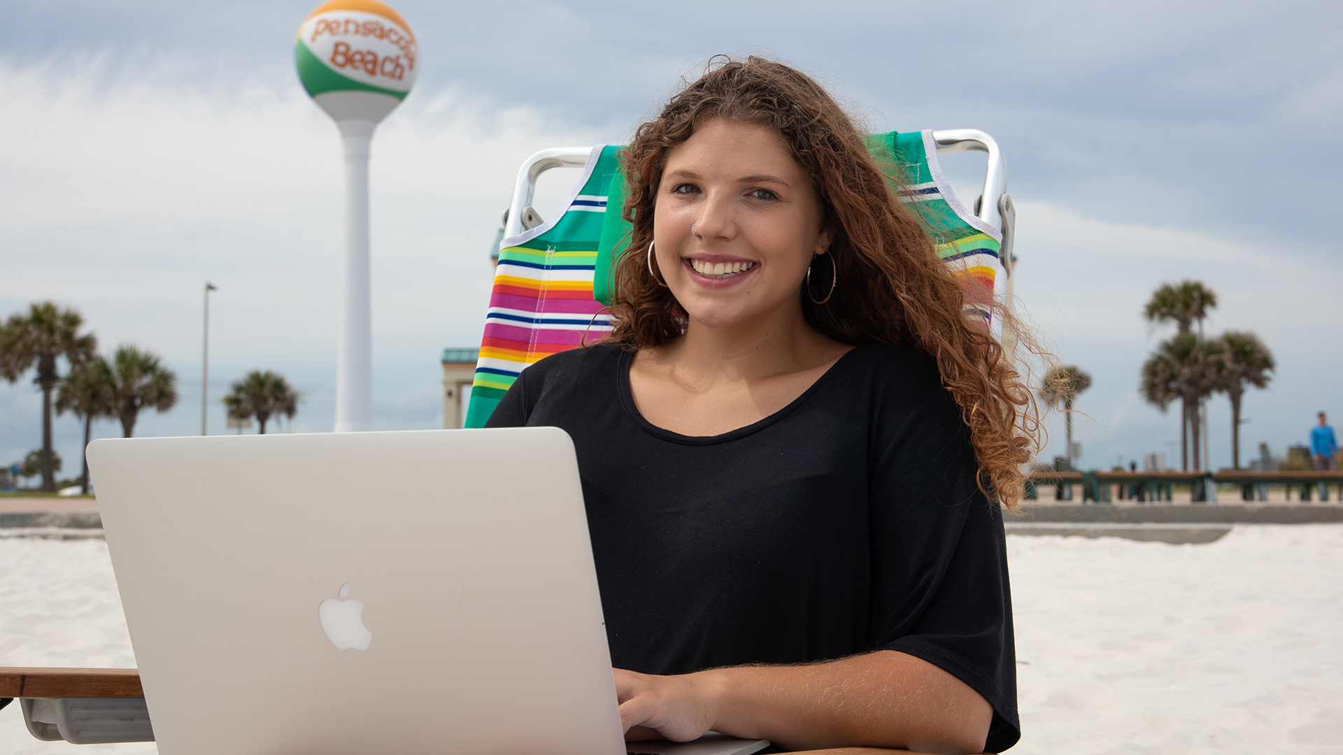 Student using library resources remotely while relaxing on the beach.