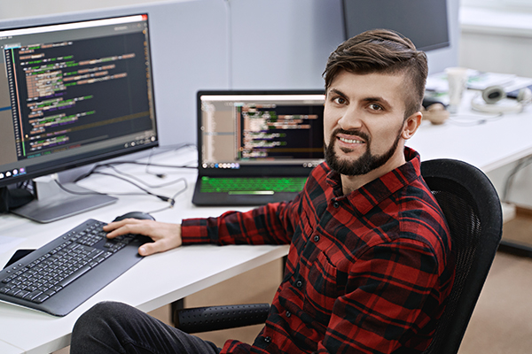 Software developer at desk smiling at camera