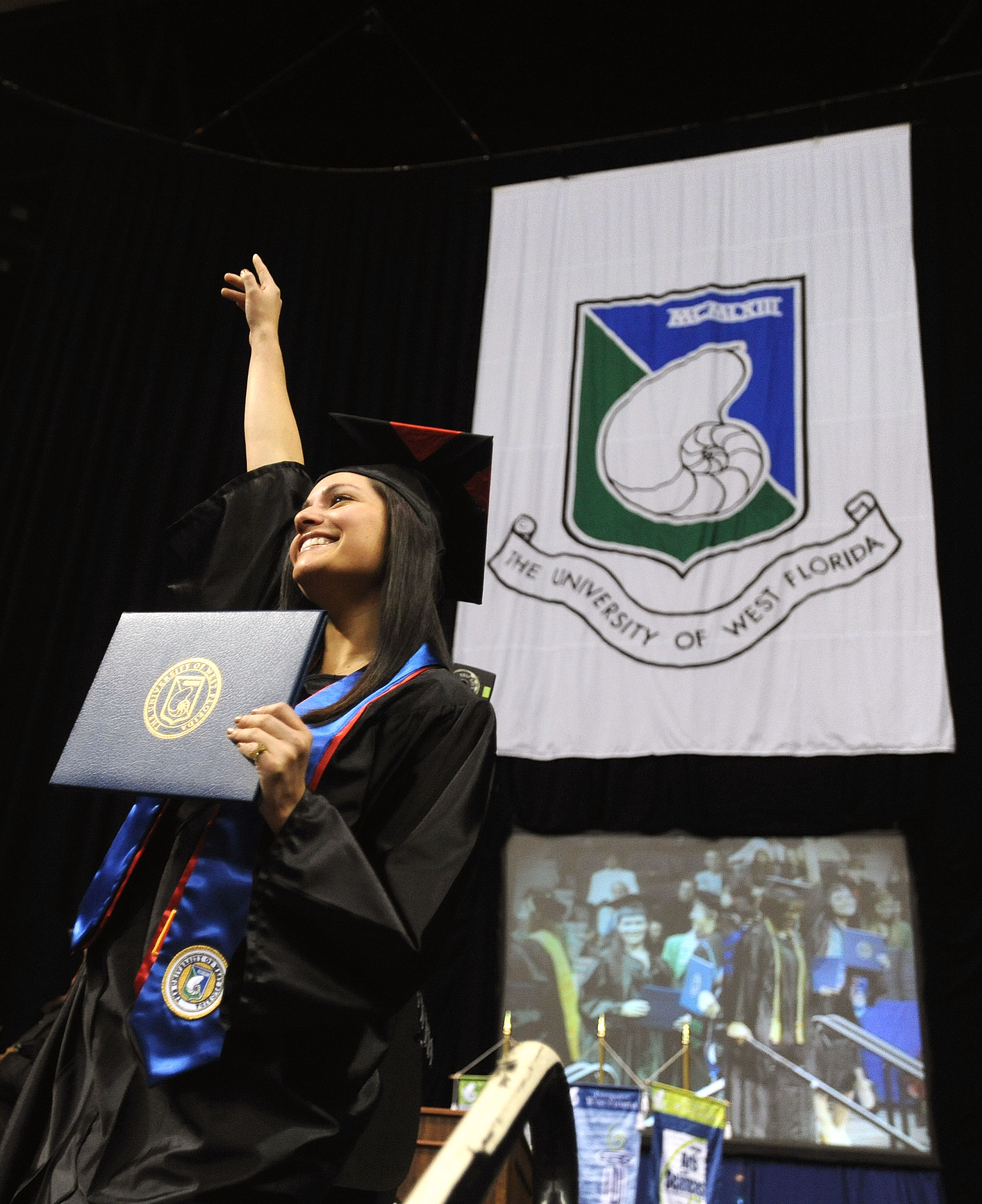 A student proudly displays a diploma cover during commencement.