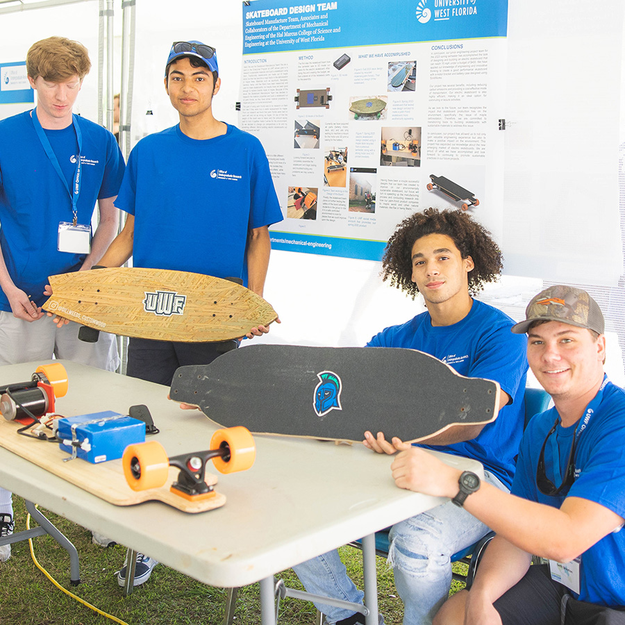 Four students presenting battery powered skateboards during a research symposium.