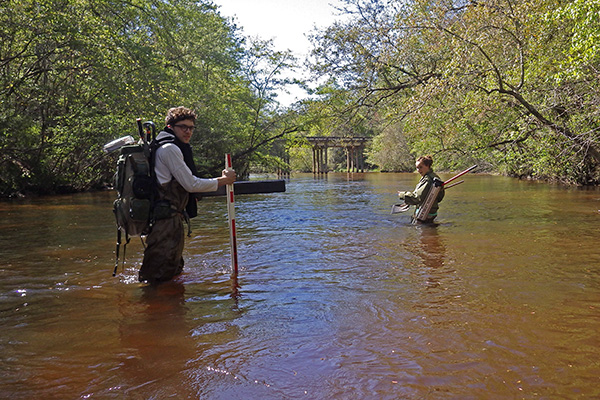 students wading through a local river taking water samples