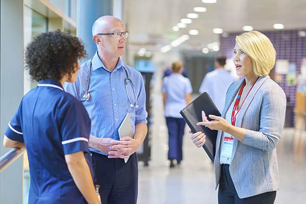 healthcare administrator, nurse, and doctor have a conversation in a hospital lobby 