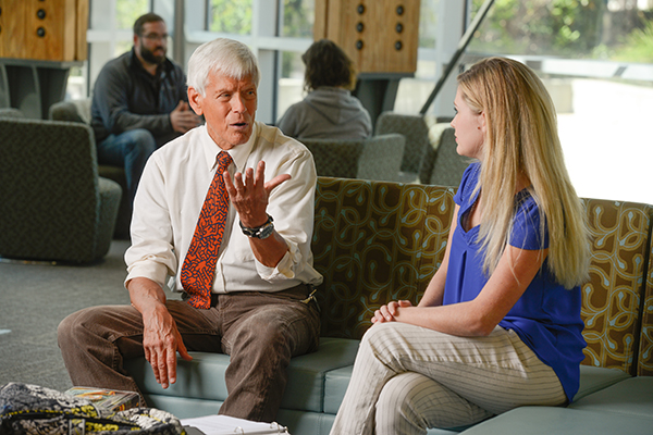 marketing professor conversing with a student in the college of business atrium