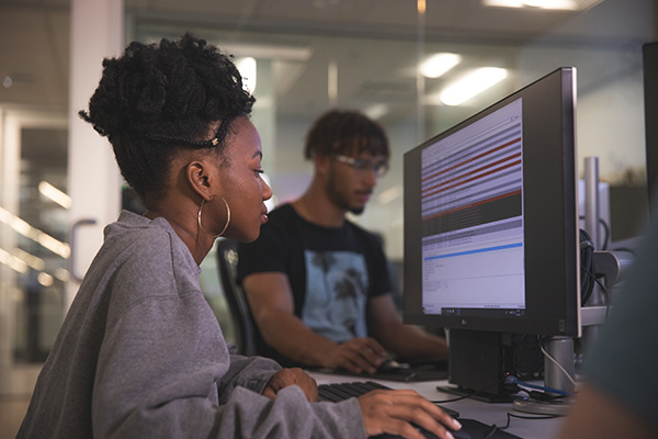 Two cybersecurity students working at computers.